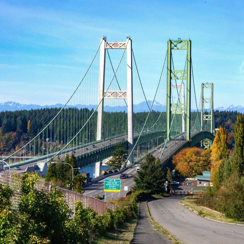 Tacoma Narrows suspension bridges with forested hills and snow-capped mountains in Washington State
